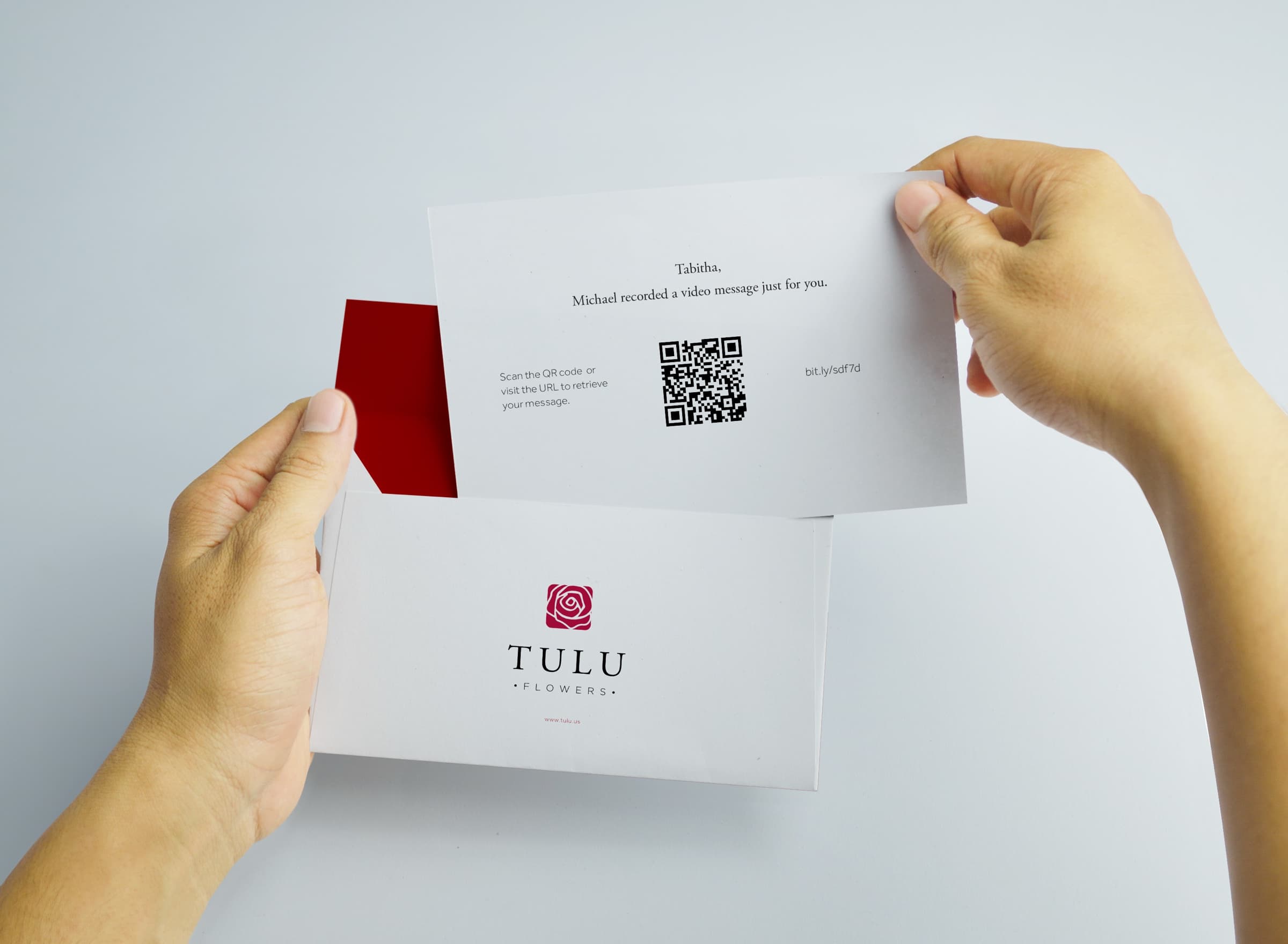 Hands opening a Tulu card with a QR code linking to a video message